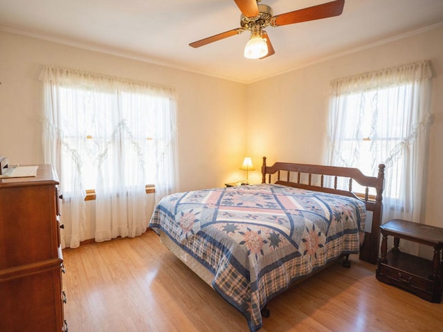 bedroom with light wood finished floors, crown molding, and ceiling fan