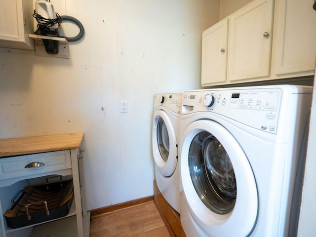 laundry area with light wood finished floors, cabinet space, baseboards, and separate washer and dryer