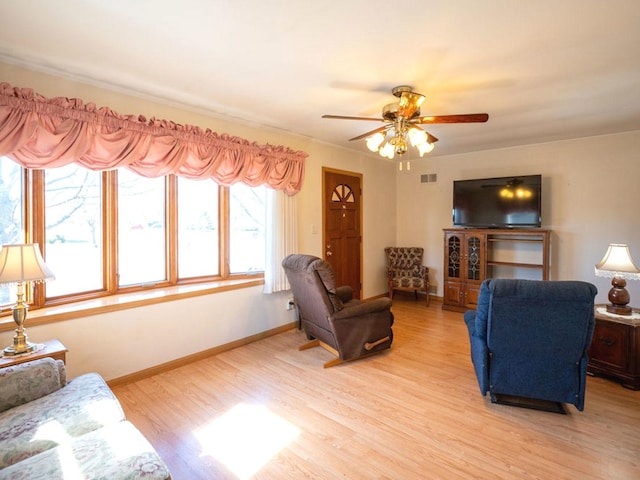 living room with light wood-type flooring, baseboards, visible vents, and ceiling fan