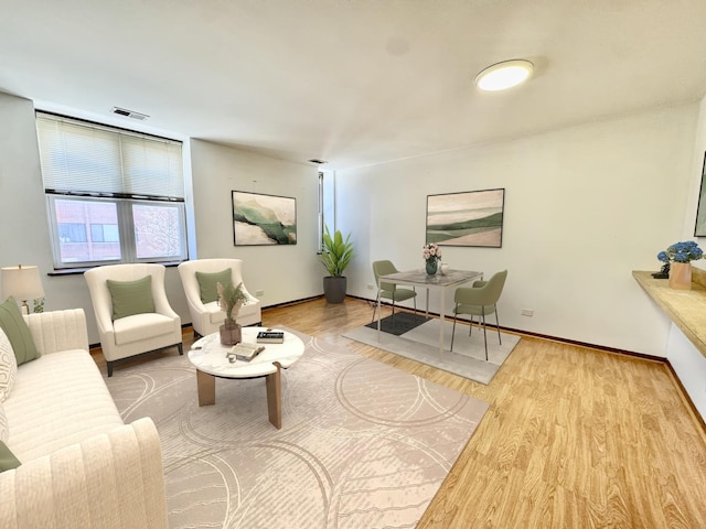 living room featuring visible vents, baseboards, and wood finished floors