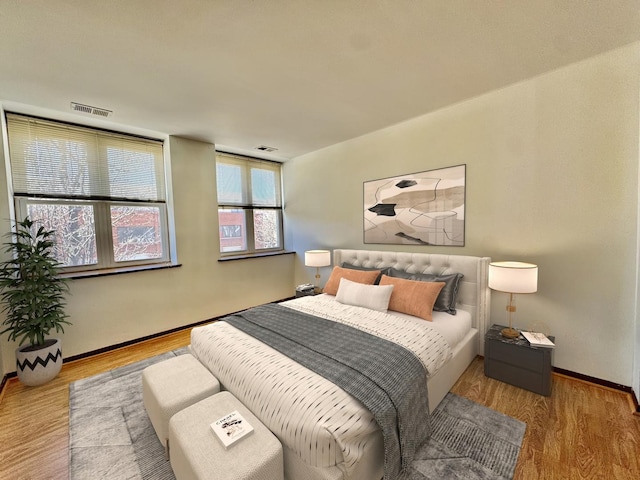 bedroom with visible vents, baseboards, and wood finished floors