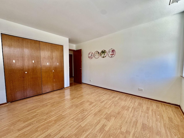 unfurnished bedroom with light wood-style floors, a closet, and baseboards