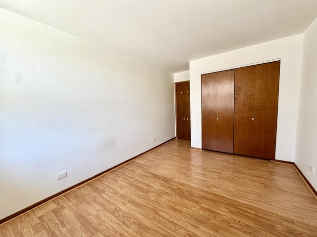 unfurnished bedroom with light wood-style floors, baseboards, and a closet