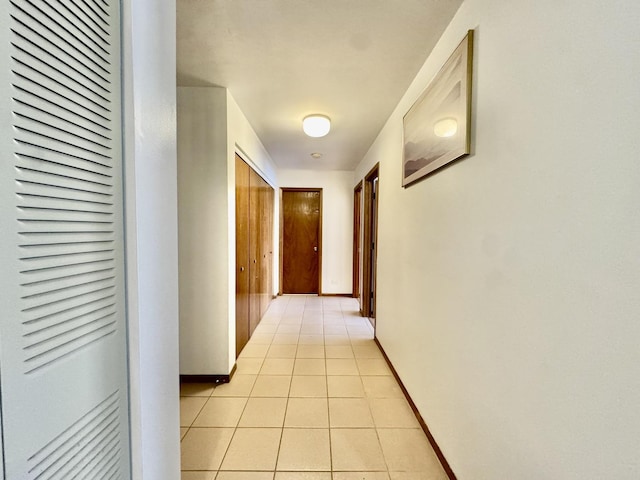 corridor featuring light tile patterned floors and baseboards