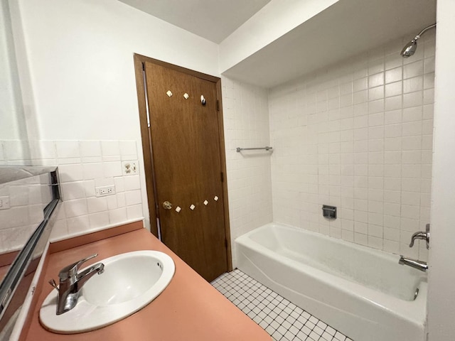 bathroom featuring shower / bathing tub combination, tile patterned flooring, a sink, and tile walls