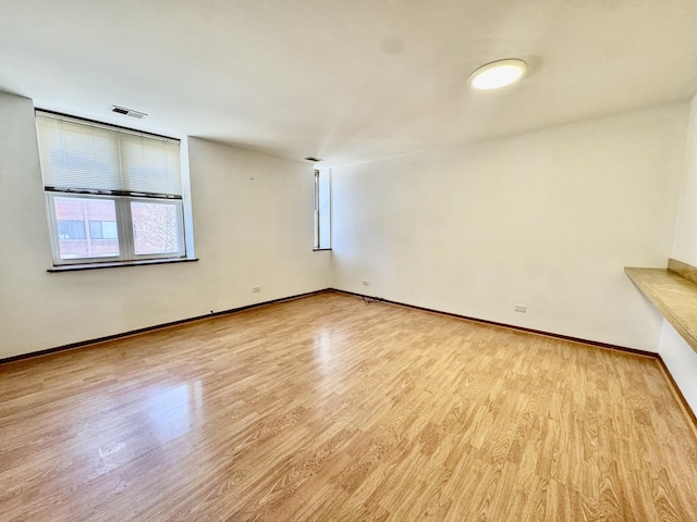 unfurnished room with visible vents, light wood-style flooring, and baseboards