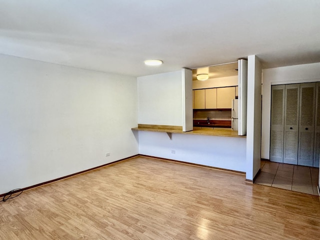 interior space featuring a sink, baseboards, and wood finished floors