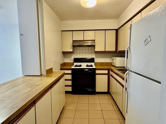 kitchen featuring white appliances, cream cabinetry, under cabinet range hood, backsplash, and light tile patterned flooring