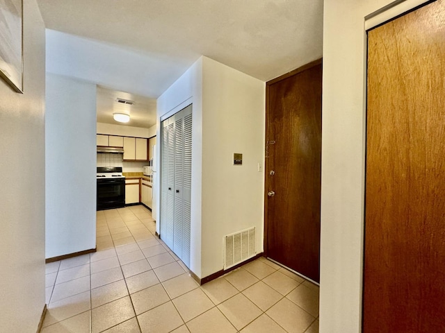 hallway featuring visible vents, baseboards, and light tile patterned floors