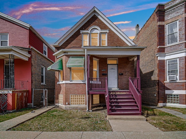 view of front of home featuring cooling unit, covered porch, and brick siding