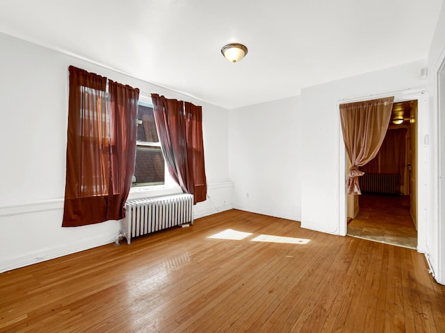 spare room featuring hardwood / wood-style floors and radiator heating unit