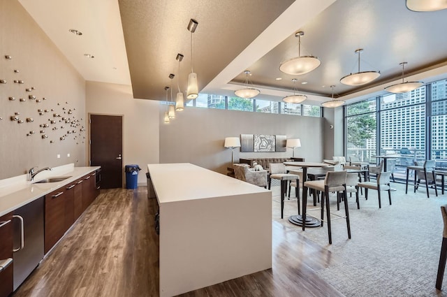 kitchen featuring a center island, modern cabinets, light countertops, a sink, and wood finished floors