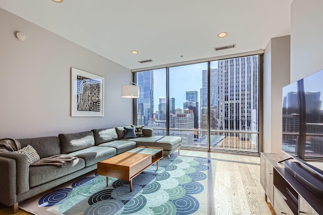 living area featuring a wall of windows, recessed lighting, visible vents, and light wood-style floors