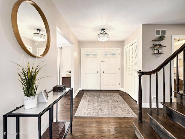 foyer with stairway, baseboards, visible vents, and dark wood-style flooring