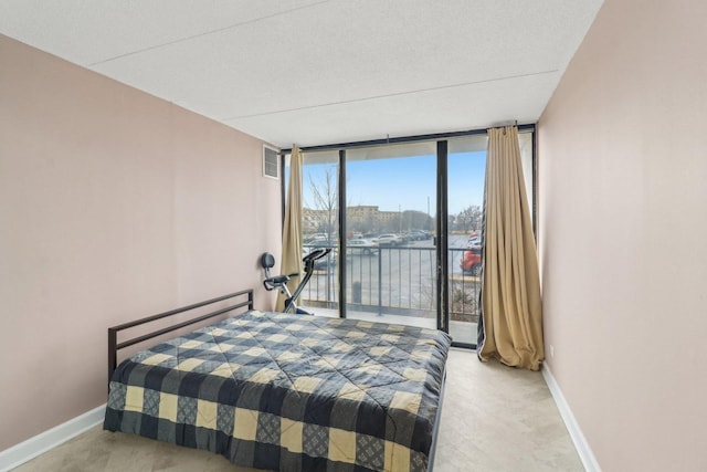 bedroom featuring access to exterior, floor to ceiling windows, visible vents, and baseboards