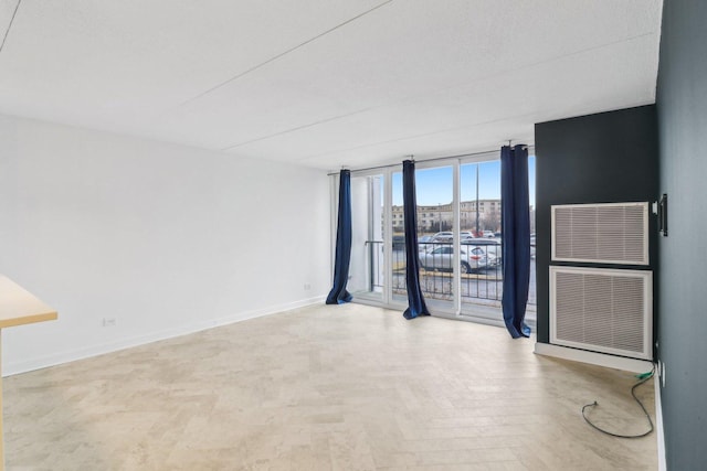 unfurnished room with baseboards and expansive windows