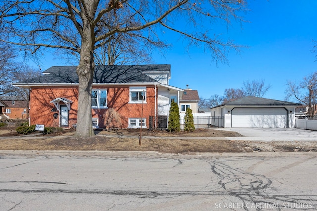 view of front of home featuring a detached garage, brick siding, an outdoor structure, and fence