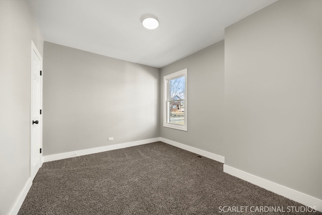 spare room with dark carpet and baseboards