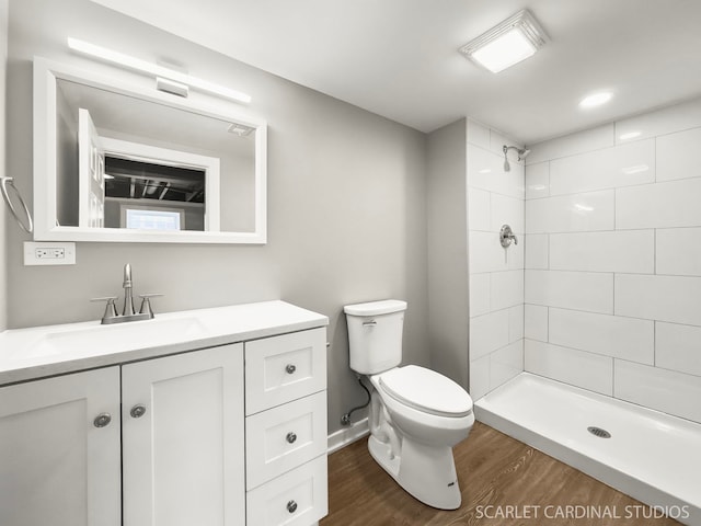 full bath with a tile shower, toilet, vanity, and wood finished floors