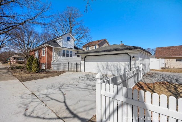 exterior space with an outdoor structure, brick siding, a garage, and a fenced front yard