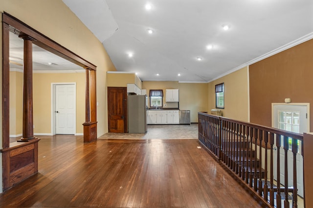 interior space with baseboards, lofted ceiling, decorative columns, dark wood-type flooring, and crown molding