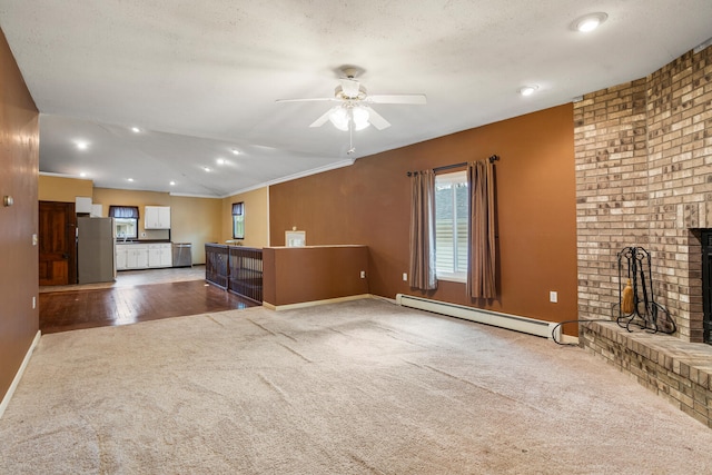 unfurnished living room featuring baseboards, a baseboard radiator, a fireplace, ceiling fan, and carpet flooring