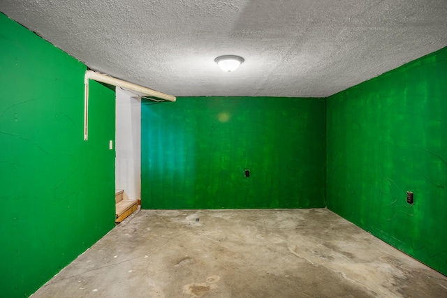 spare room with unfinished concrete floors, a textured ceiling, and stairs