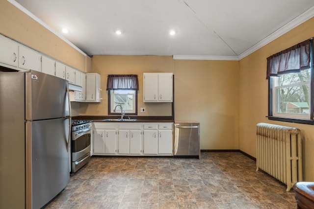 kitchen with dark countertops, under cabinet range hood, radiator heating unit, stainless steel appliances, and a sink