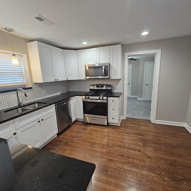 kitchen featuring tasteful backsplash, dark wood-style flooring, stainless steel appliances, and a sink