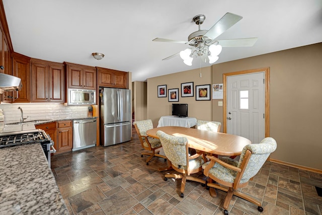 dining room featuring stone finish flooring, a ceiling fan, and baseboards