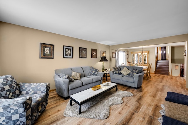 living area featuring a notable chandelier, stairway, and light wood-style floors