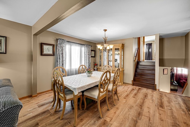 dining space with light wood-type flooring, stairs, baseboards, and a notable chandelier