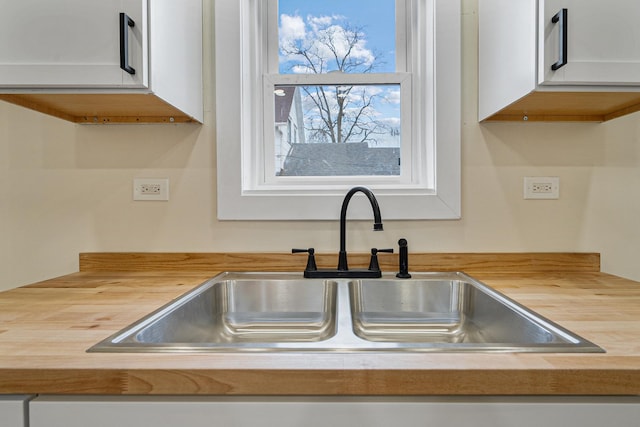 kitchen featuring butcher block counters, a sink, and white cabinets