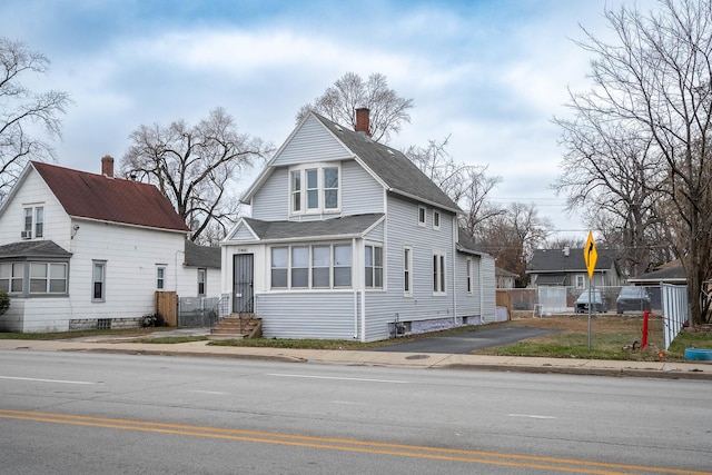 view of front of property featuring entry steps, a chimney, fence, and roof with shingles