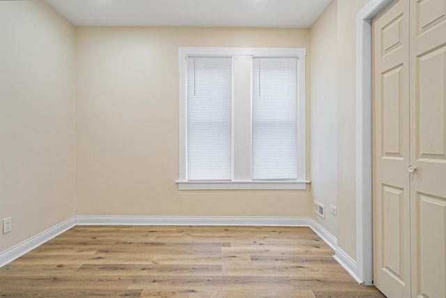 empty room featuring visible vents, baseboards, and wood finished floors