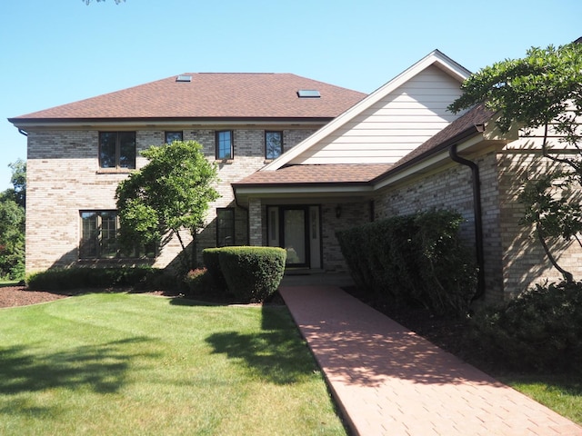 view of front of home featuring roof with shingles, a front lawn, and brick siding