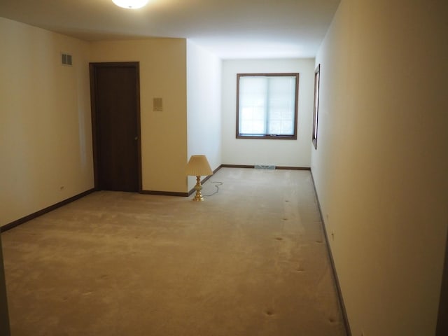 spare room featuring light carpet, visible vents, and baseboards