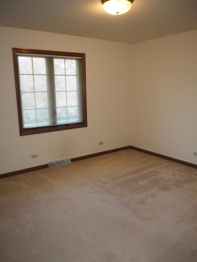 spare room with baseboards, visible vents, and light colored carpet