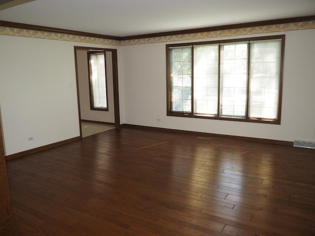 empty room with hardwood / wood-style floors, visible vents, and baseboards