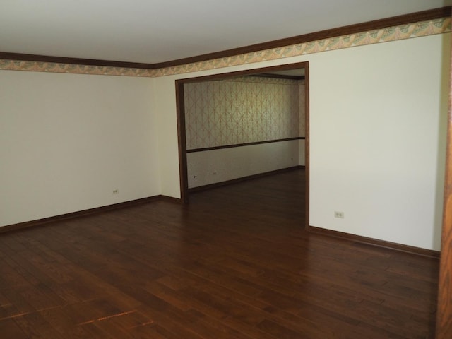 empty room with dark wood-type flooring, crown molding, and baseboards