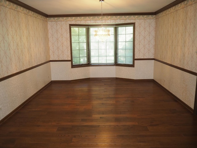 spare room featuring dark wood finished floors, an inviting chandelier, and wallpapered walls