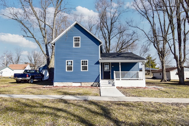 traditional home with covered porch, a front yard, and roof with shingles