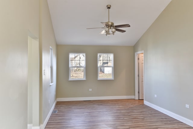 empty room featuring baseboards, wood finished floors, a ceiling fan, and vaulted ceiling