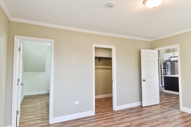 unfurnished bedroom featuring ornamental molding, light wood-style floors, stainless steel refrigerator with ice dispenser, and baseboards