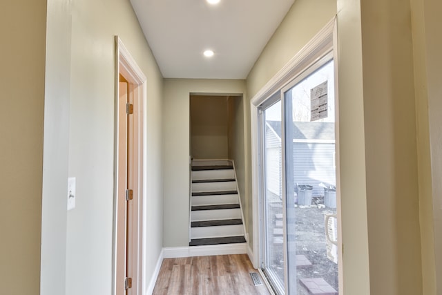 hallway with baseboards, stairs, and light wood finished floors