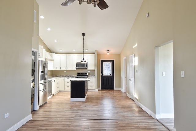 kitchen featuring light wood-style floors, stainless steel appliances, baseboards, and a kitchen island