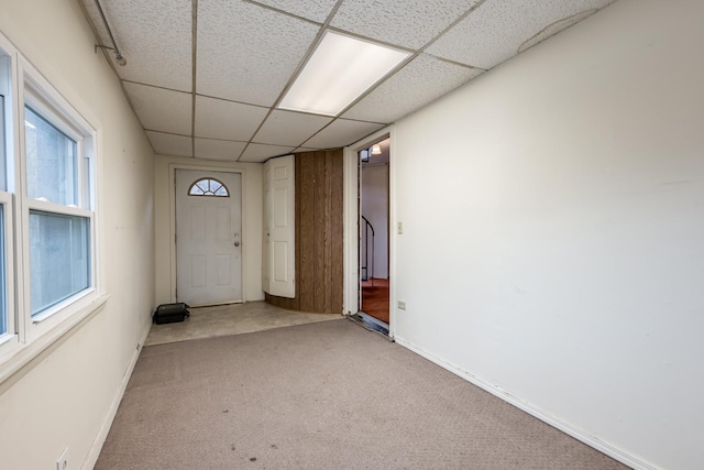 interior space with baseboards, a drop ceiling, and carpet flooring