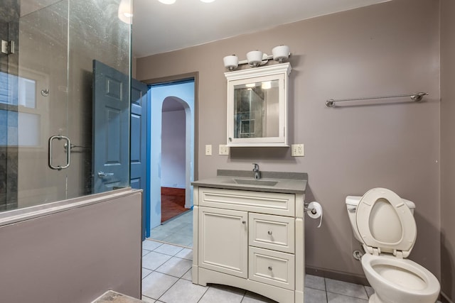 bathroom featuring tile patterned flooring, toilet, vanity, baseboards, and a stall shower