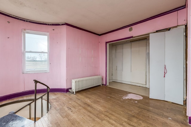 unfurnished bedroom featuring ornamental molding, radiator heating unit, and hardwood / wood-style flooring