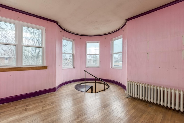 spare room featuring ornamental molding, radiator heating unit, hardwood / wood-style flooring, and baseboards